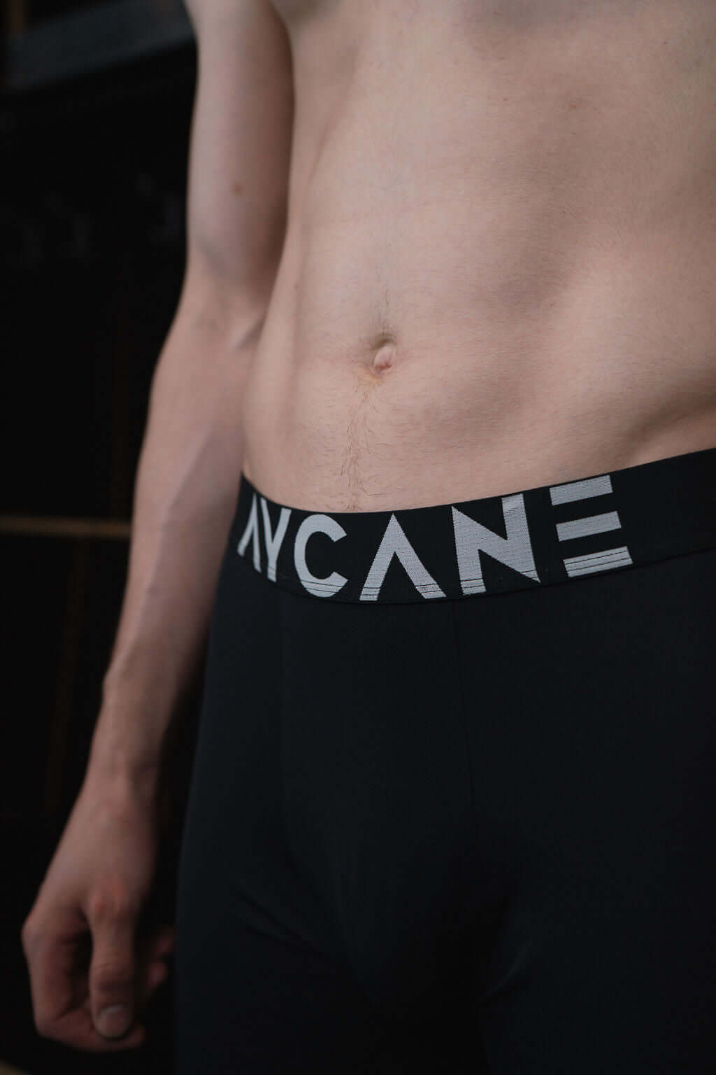 Close-up of a male model wearing black boxer briefs with a prominent waistband.