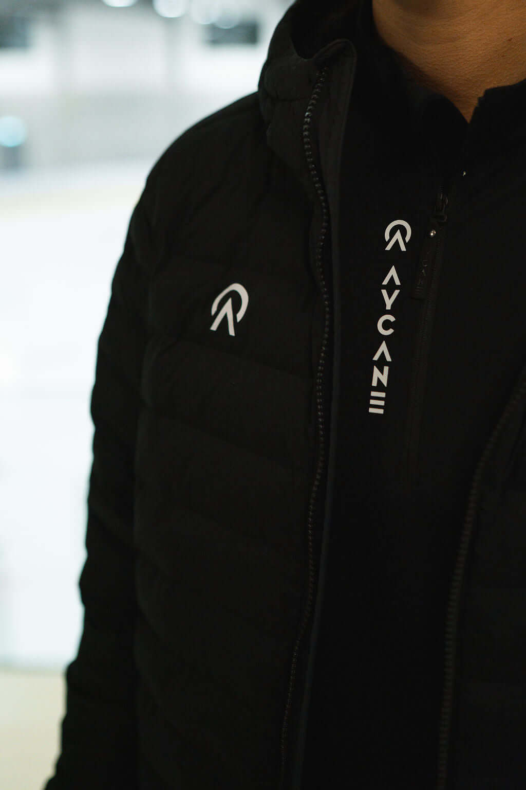 Close-up of T-Lite Jacket featuring black puffer design and logo detail, ideal for warmth and style.