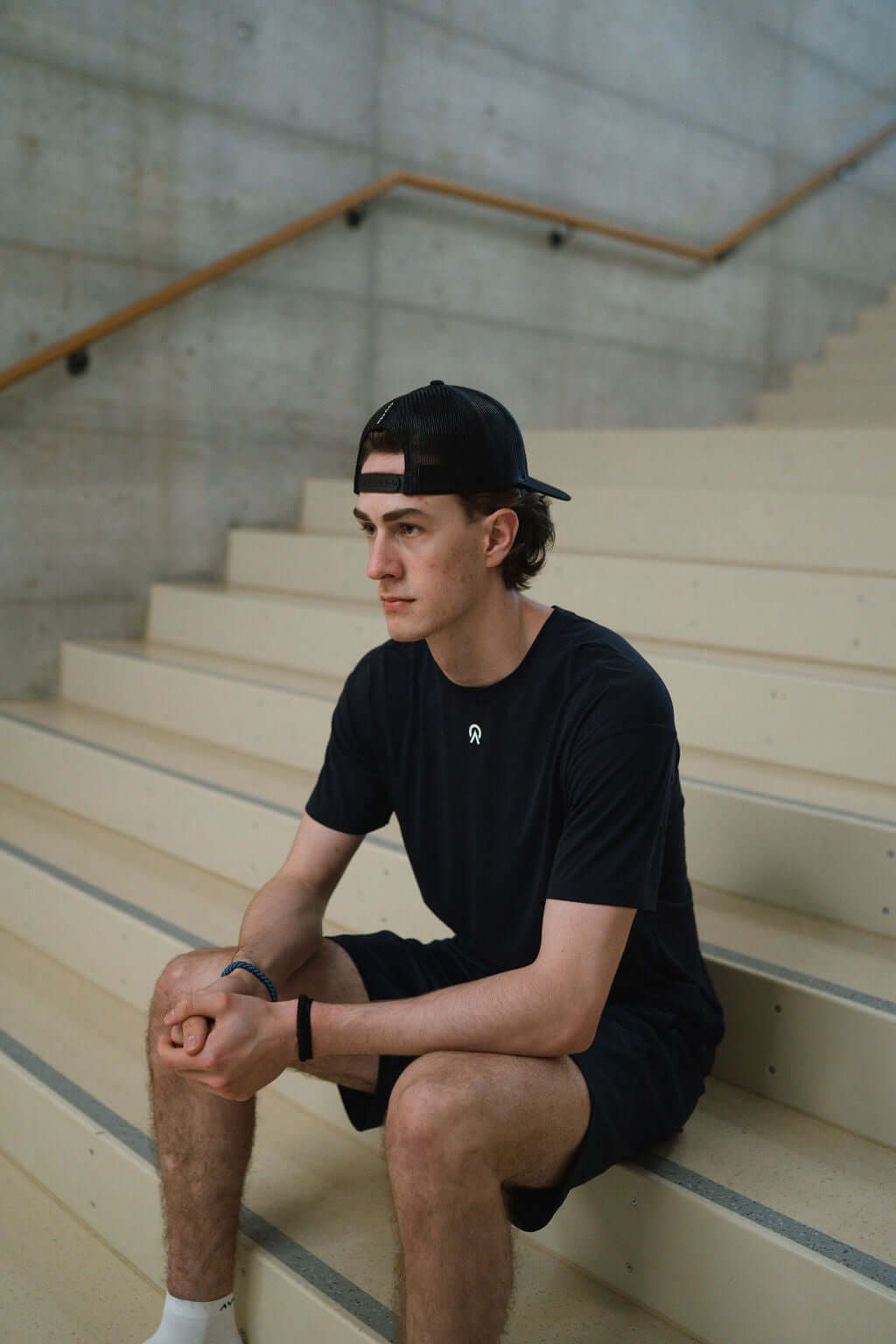 Man in black Route T-Shirt sitting on stairs, showcasing all-day comfort and athletic style.