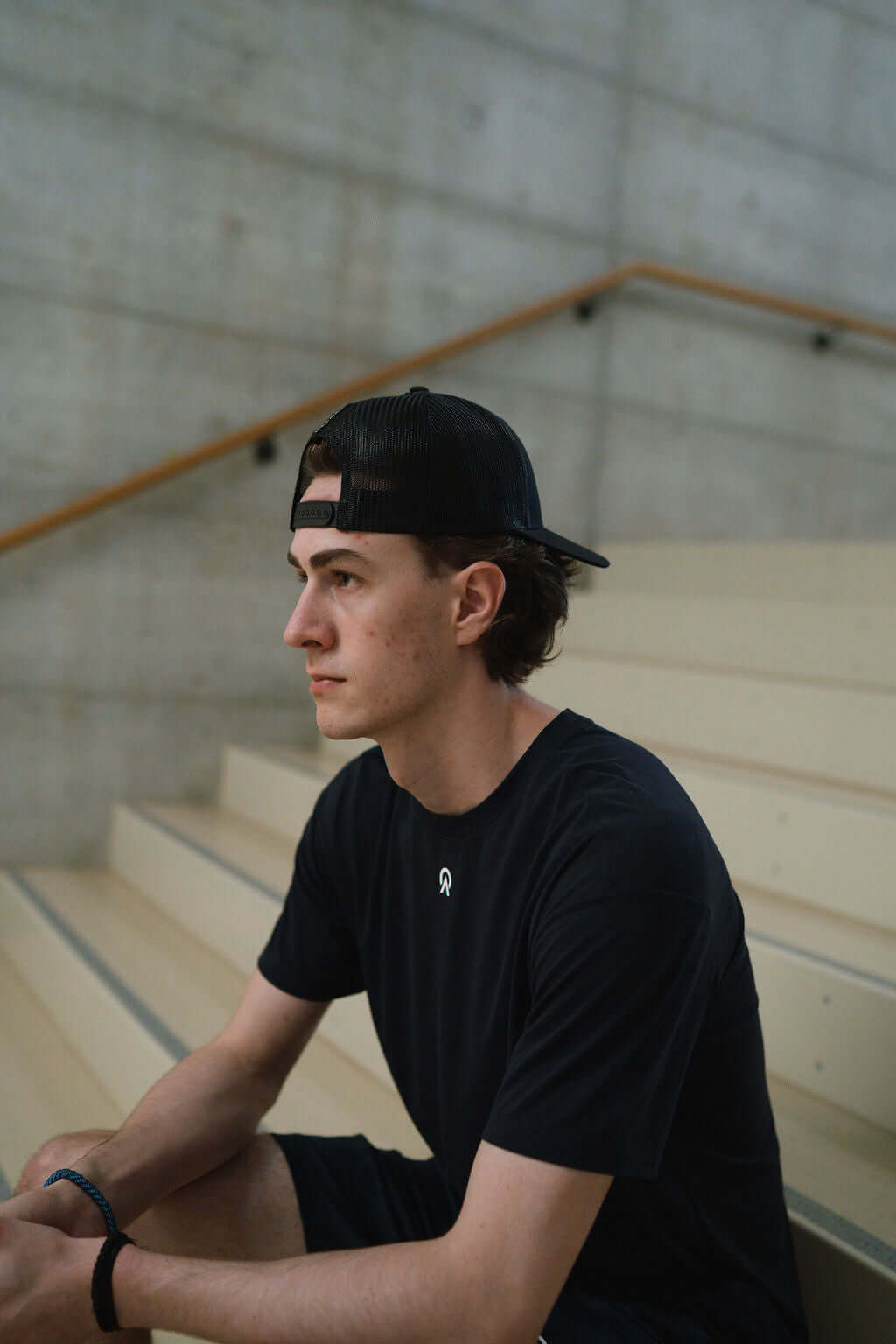 Young man wearing a black Route short sleeve t-shirt sitting on stairs, showcasing comfort and athletic style.