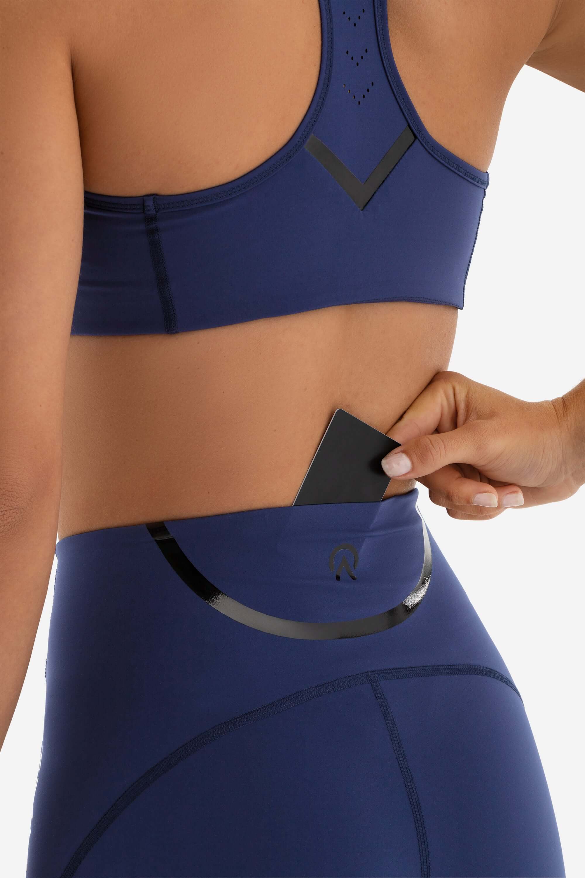 women in sports bra and short tights in blue showing the credit card pocket