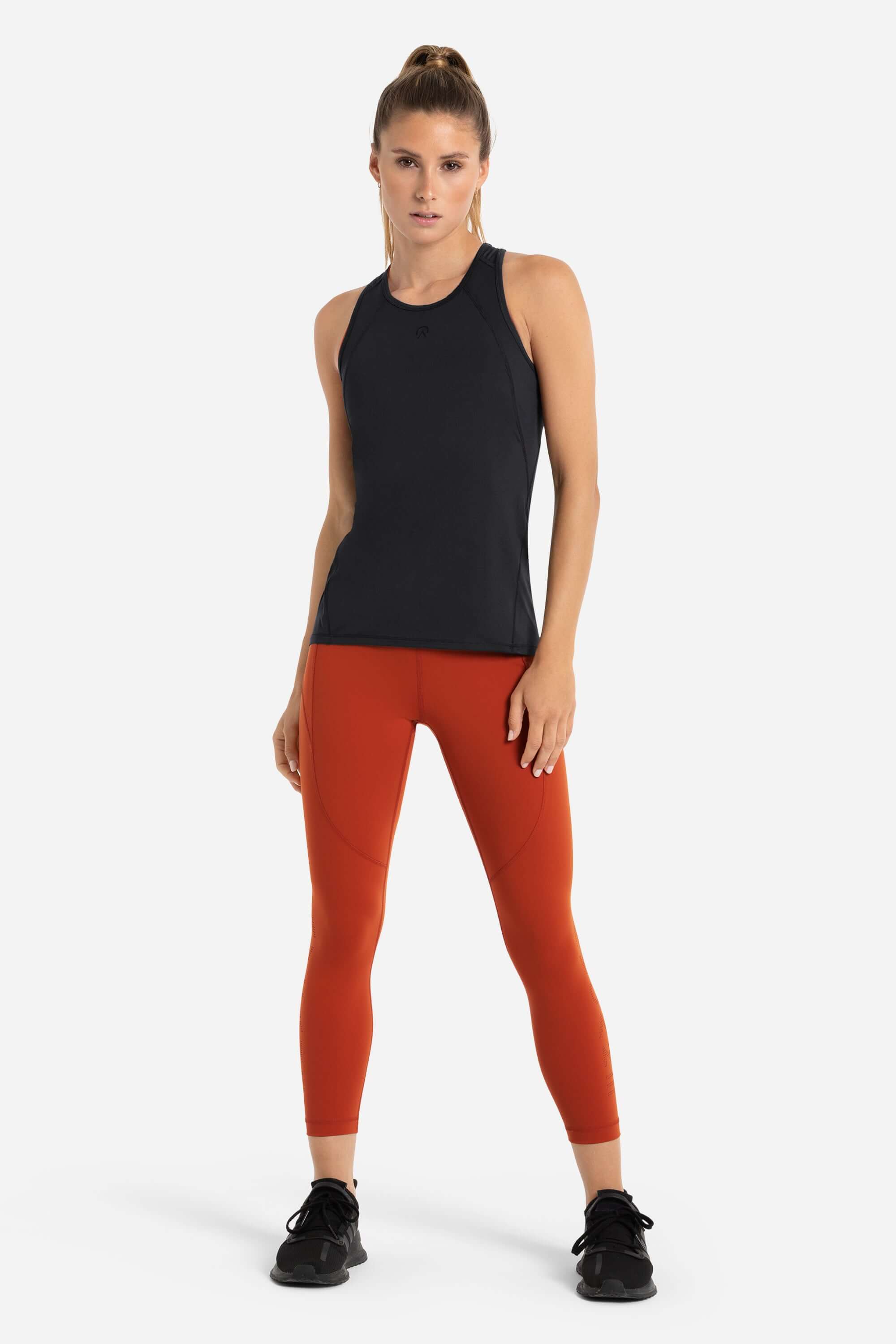 Women wearing a black workout tank top in black and red gym leggings from AYCANE