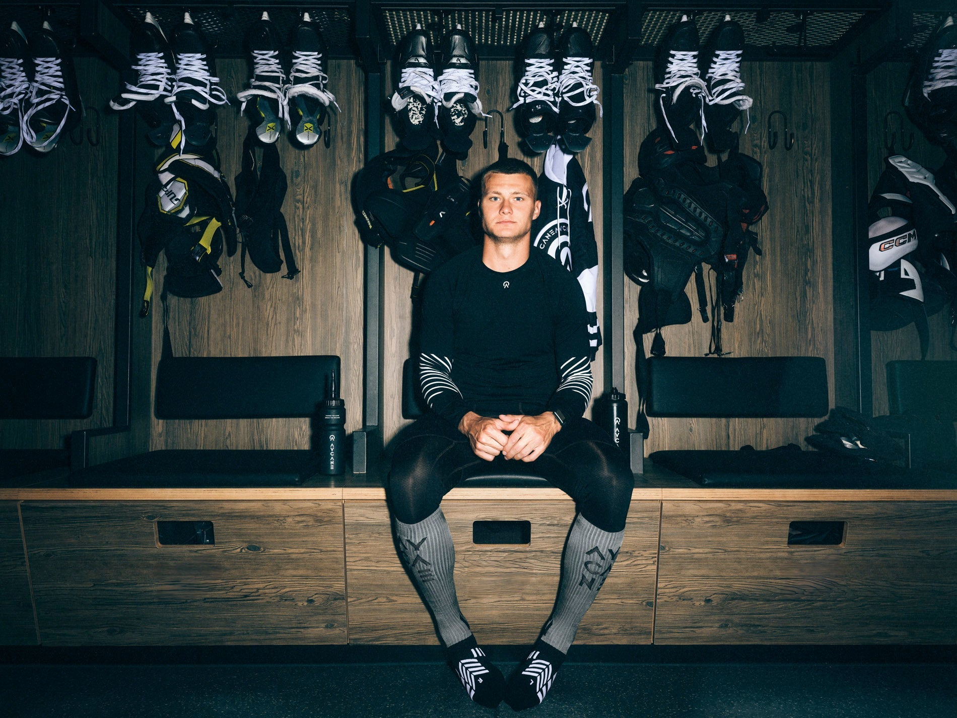 Youth competitive ice hockey players sitting shoulder to shoulder on the bench during an intense game, showing teamwork, focus, and shared struggle beyond winning.