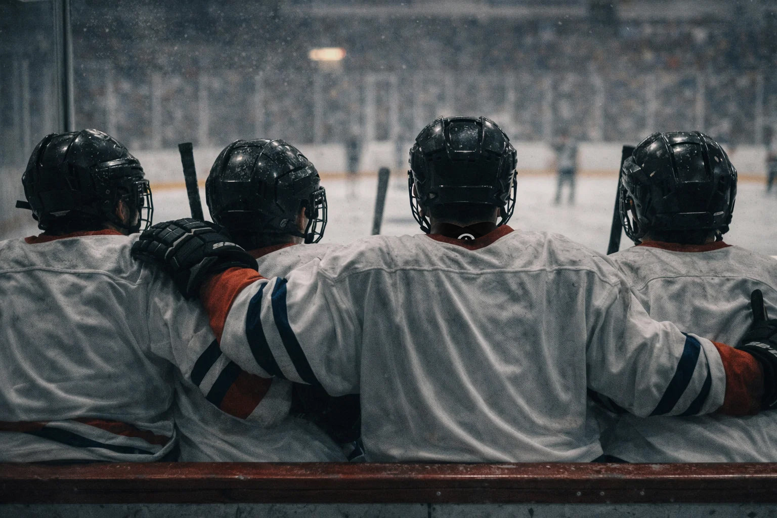 Youth competitive ice hockey players sitting shoulder to shoulder on the bench during an intense game, showing teamwork, focus, and shared struggle beyond winning.