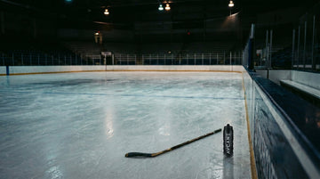 Youth and adult hockey players on an outdoor ice rink at dusk, looking toward the horizon, representing discipline, resilience, and life lessons from hockey.