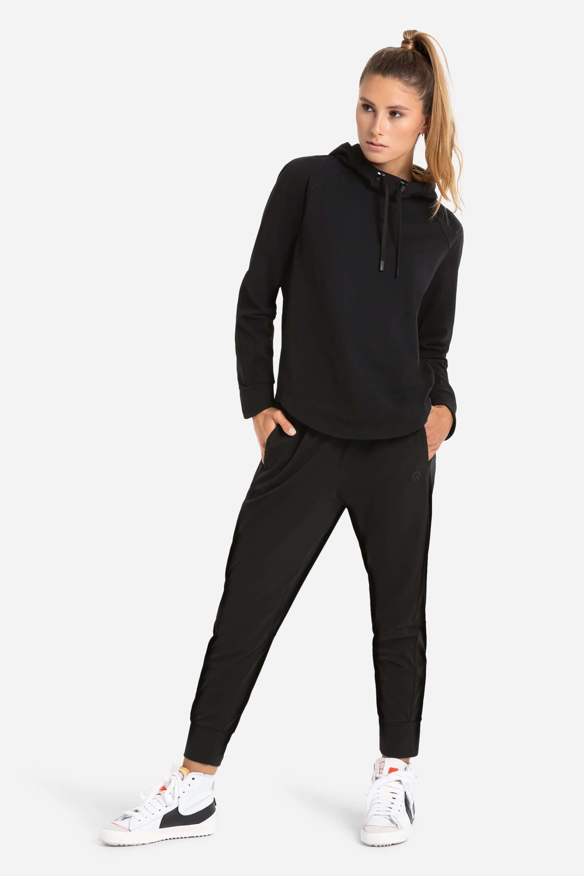 Women in a black workout hoodie and black joggers