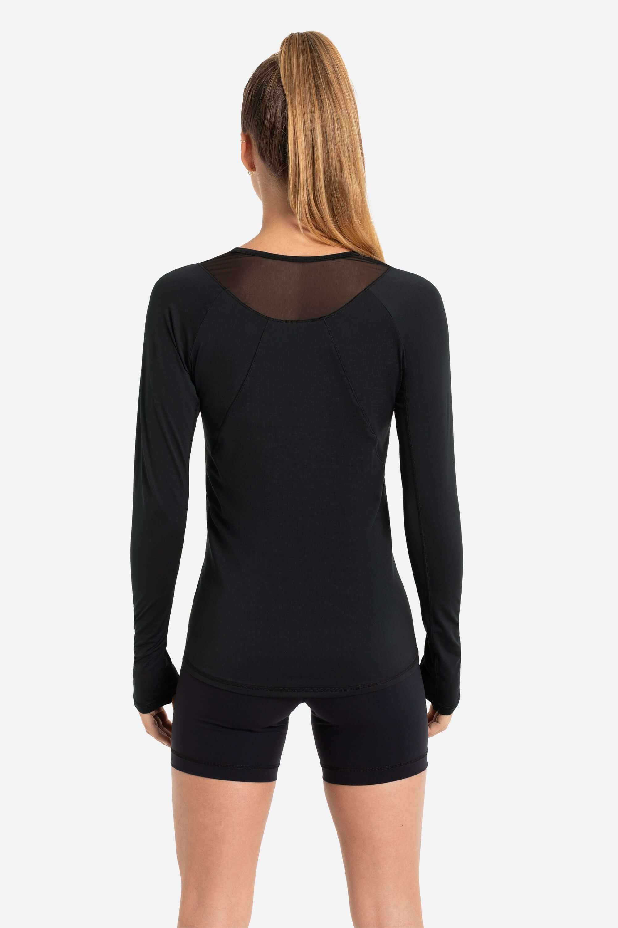 Women in a black long sleeve workout t-shirt with black short tights