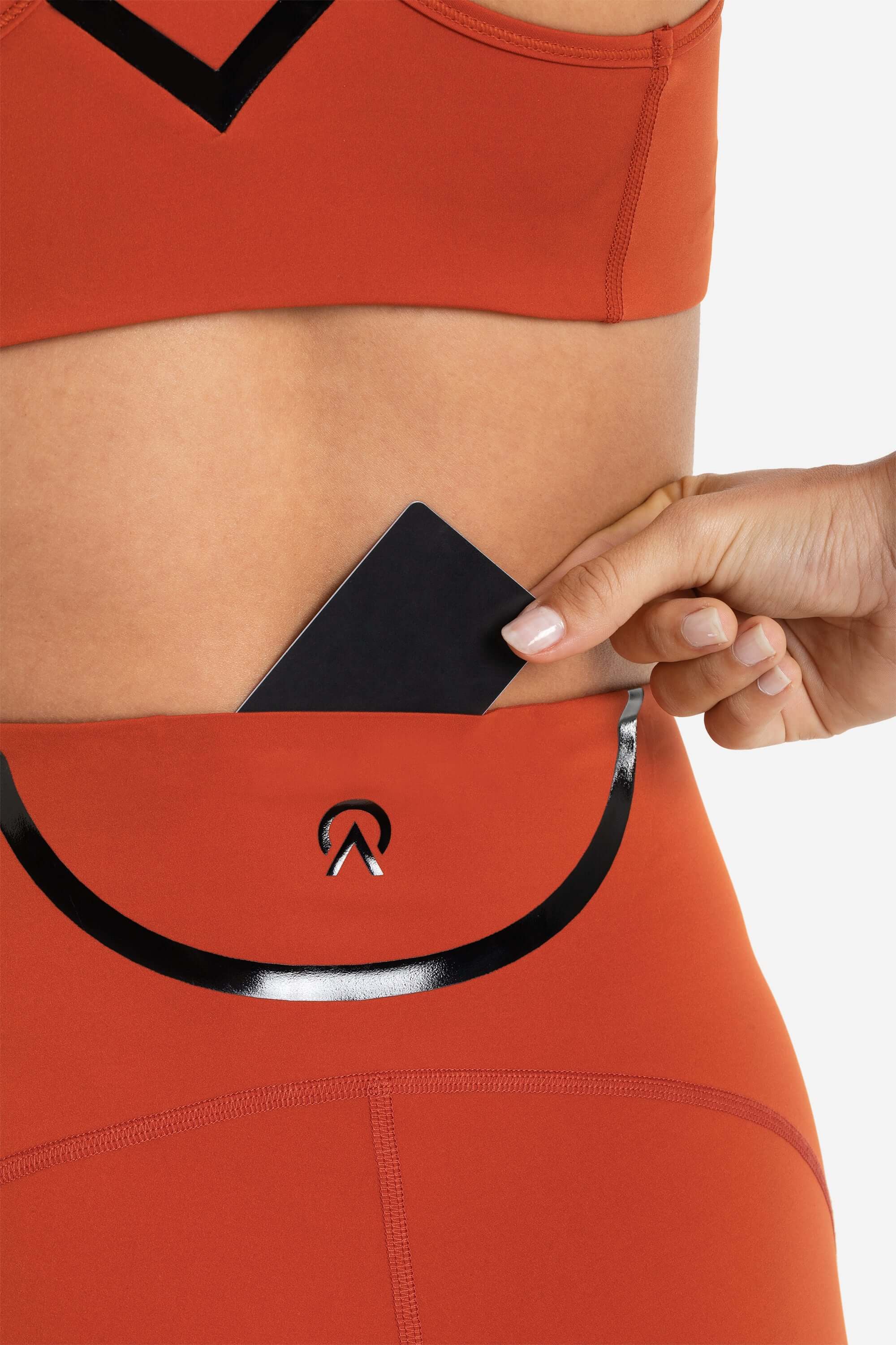 women in sports bra and short tights in red showing the credit card pocket