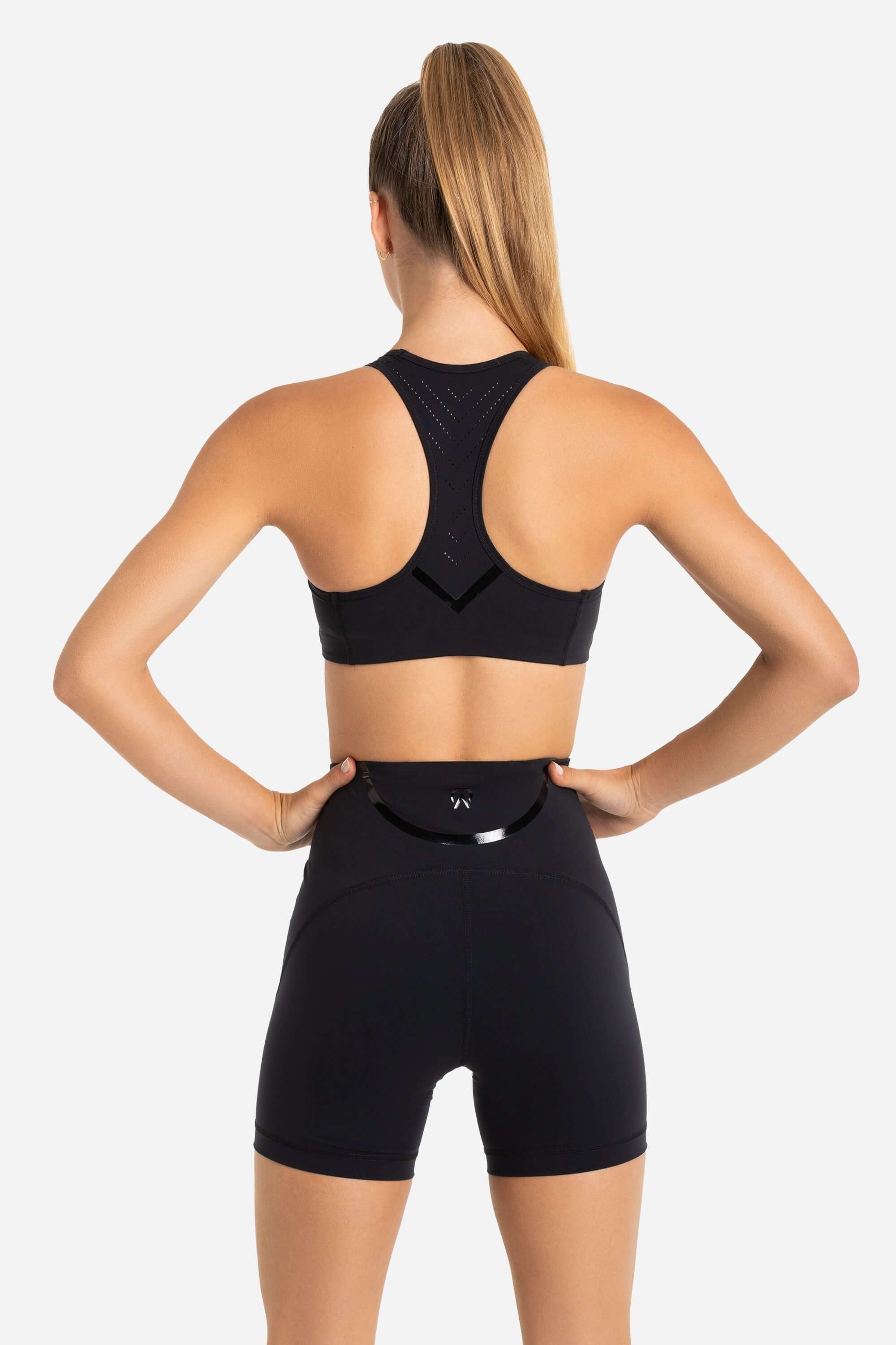 Women in a black sports bra and black short tights from AYCANE