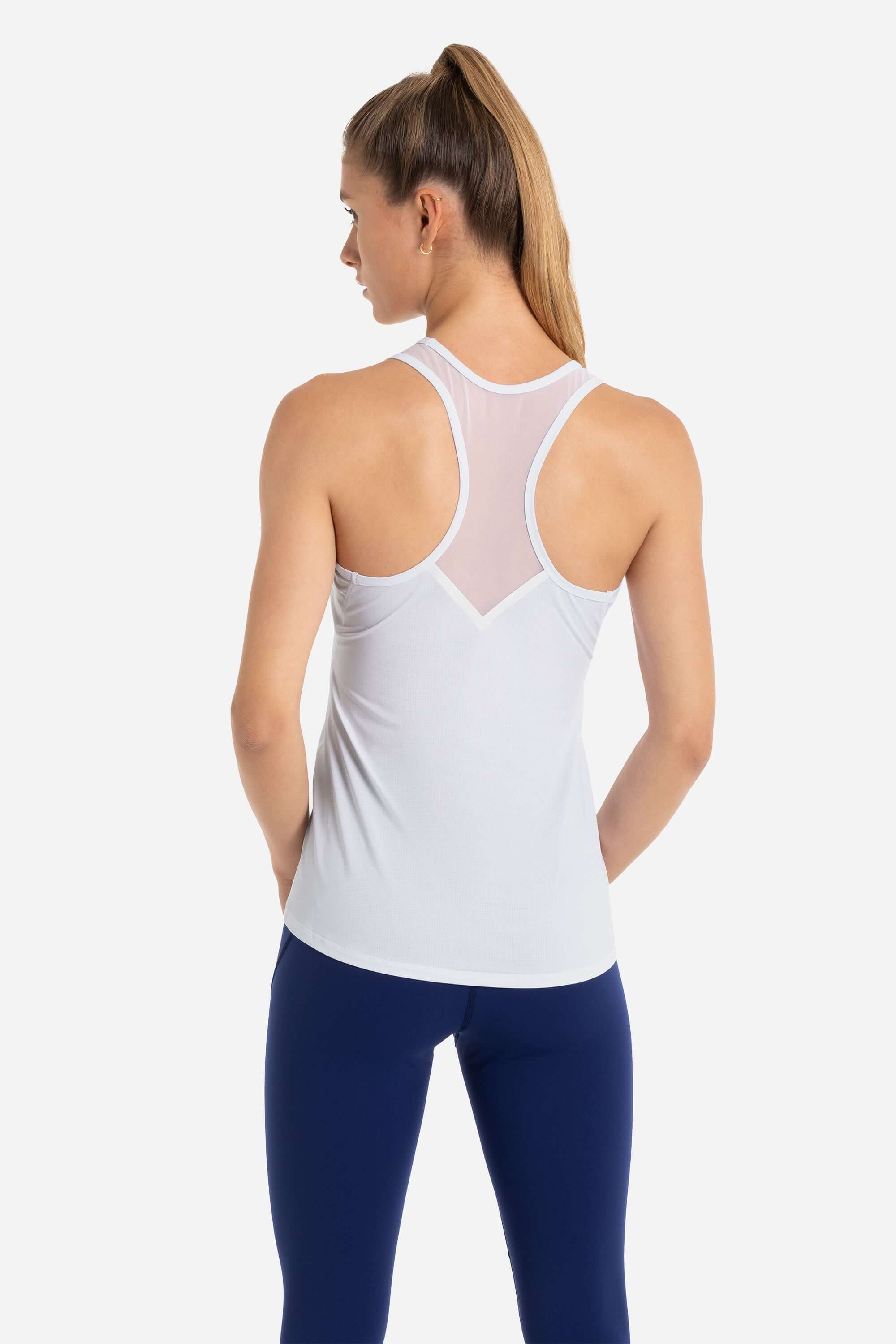 Women wearing a white workout tank top and blue gym leggings from AYCANE